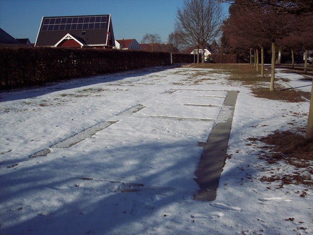 NDas Bild zeigt die gerade teilweise mit Schnee bedeckten umlaufenden Boden-platten der 5 vorbereiteten Felder für die Doppelgräber der neuen Generation.